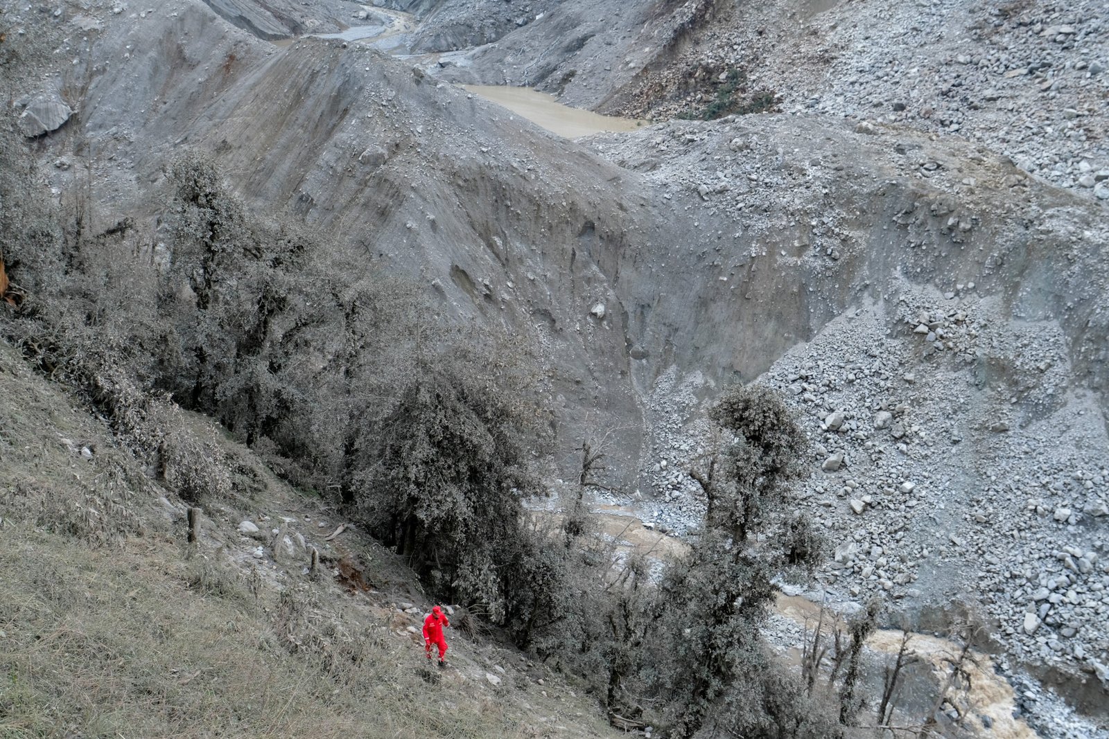 तिब्बत के ग्यिरोंग काउंटी में भूस्खलन के बाद बनी एक झील के पास एक चीनी बचावकर्मी चल रहा है।